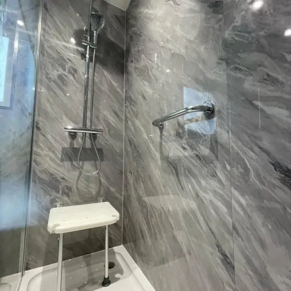 Accessible walk-in shower with grab rail, fold-down seat and slip-resistant floor by Ultimate Home Solutions