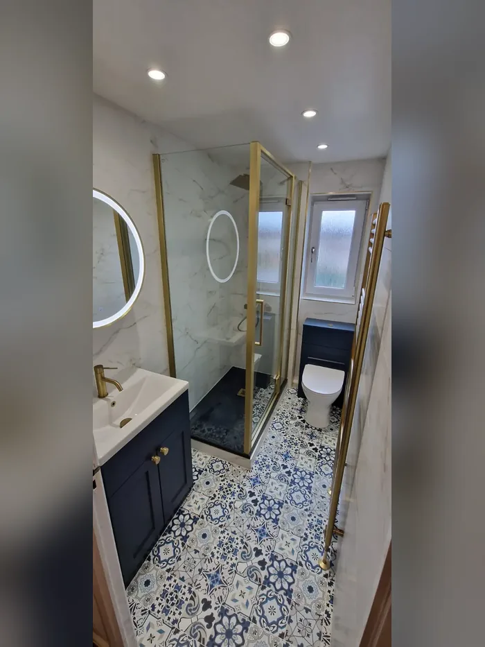 Shower room with marble-effect walls, a navy vanity, brass framed shower enclosure and back-to-wall toilet