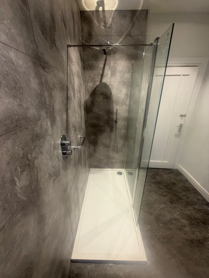 Walk-in shower with dark grey marble-effect tiles, a rainfall shower head and chrome controls