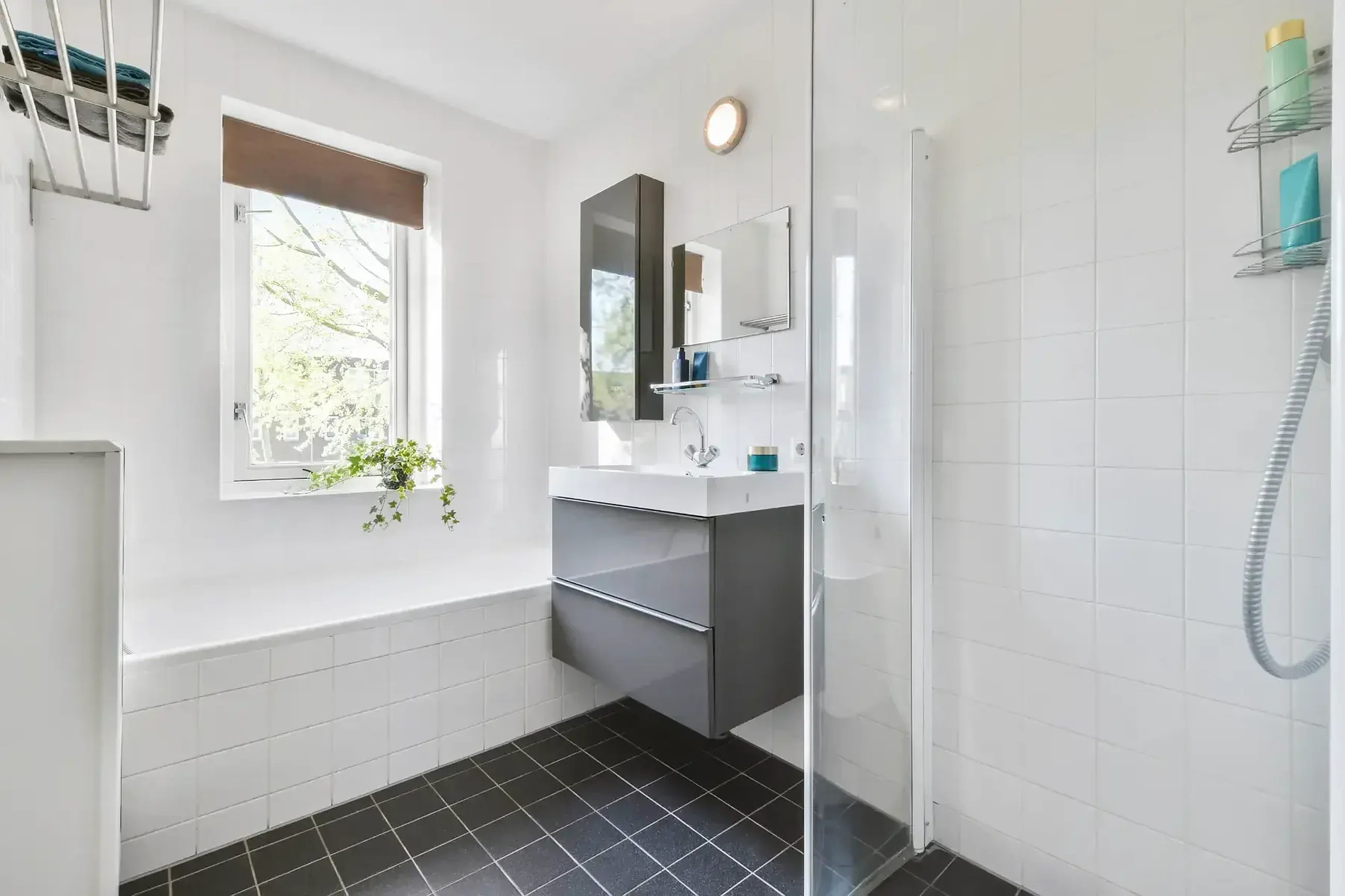 Modern fitted bathroom with bathtub, walk-in shower and grey vanity by Ultimate Home Solutions