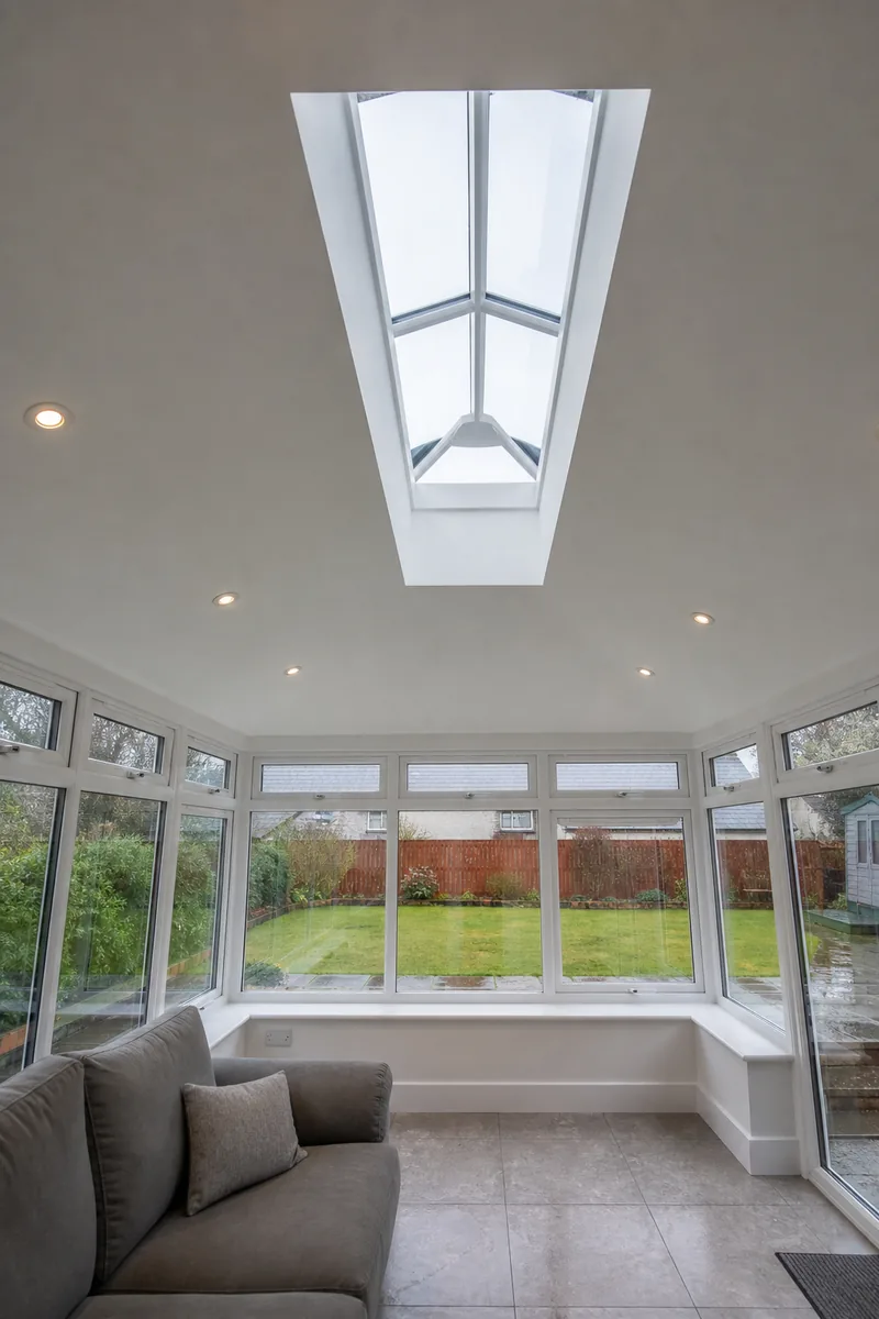 Inside a conservatory with a plastered vaulted ceiling, downlights and a glazed roof lantern
