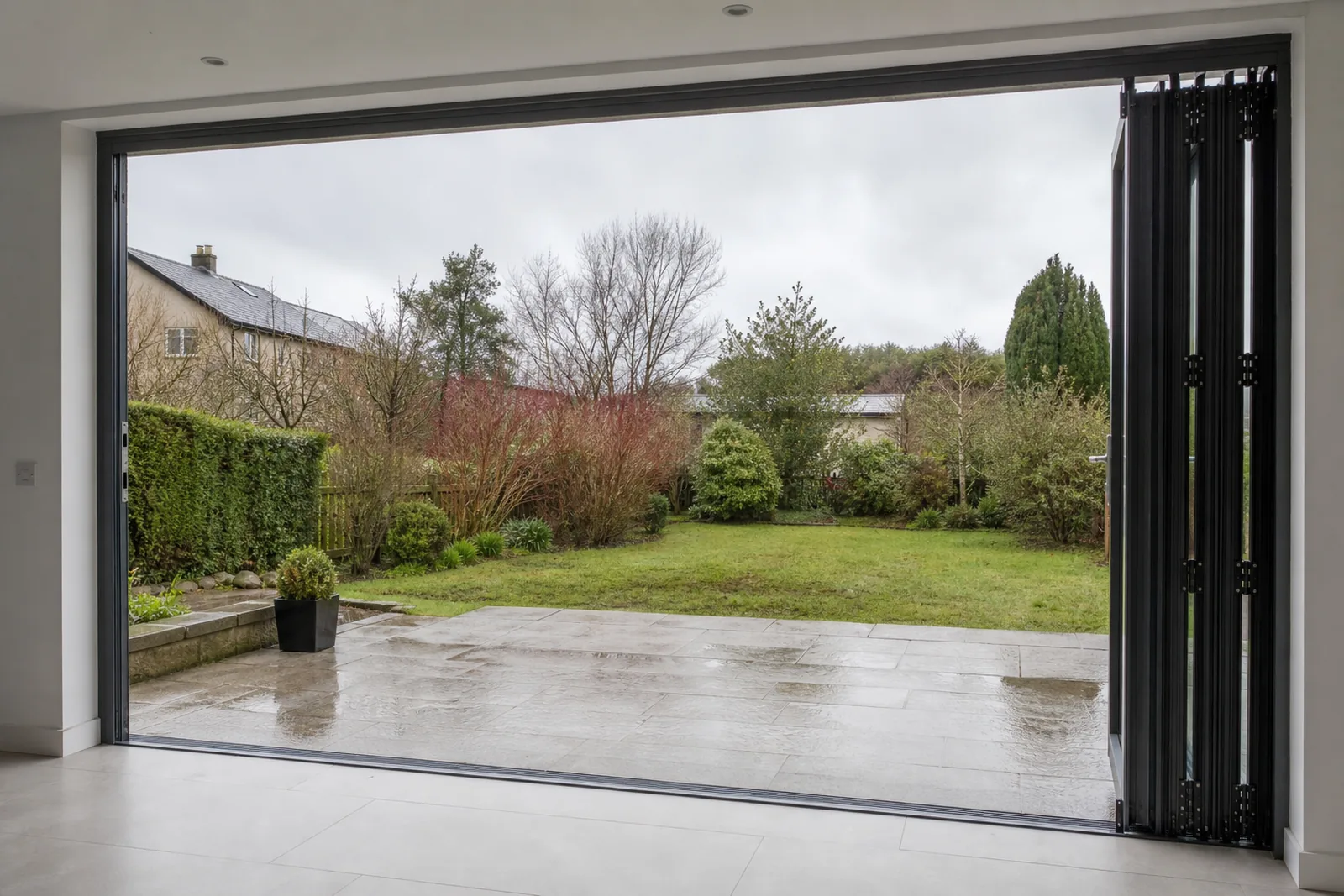 Five-panel bi-fold door folded fully open to a patio, almost the whole wall clear