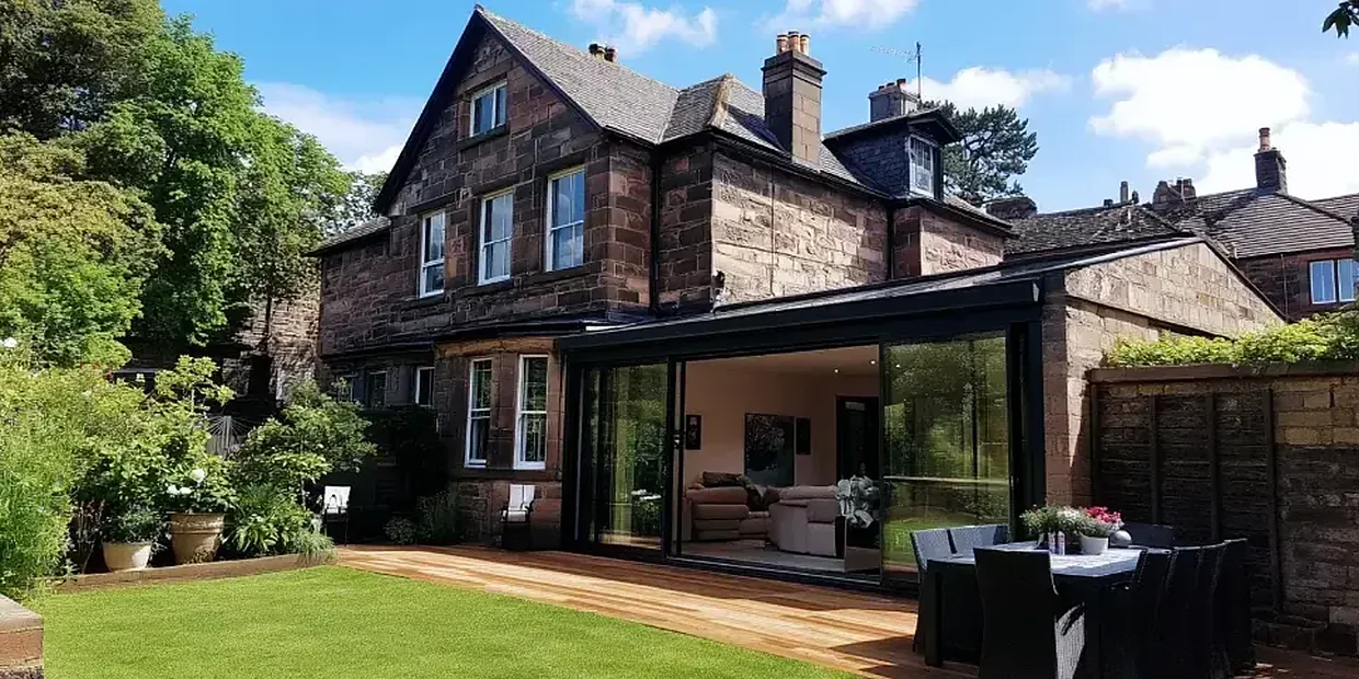 Ultra slim aluminium bi-fold doors on the back of a stone house extension
