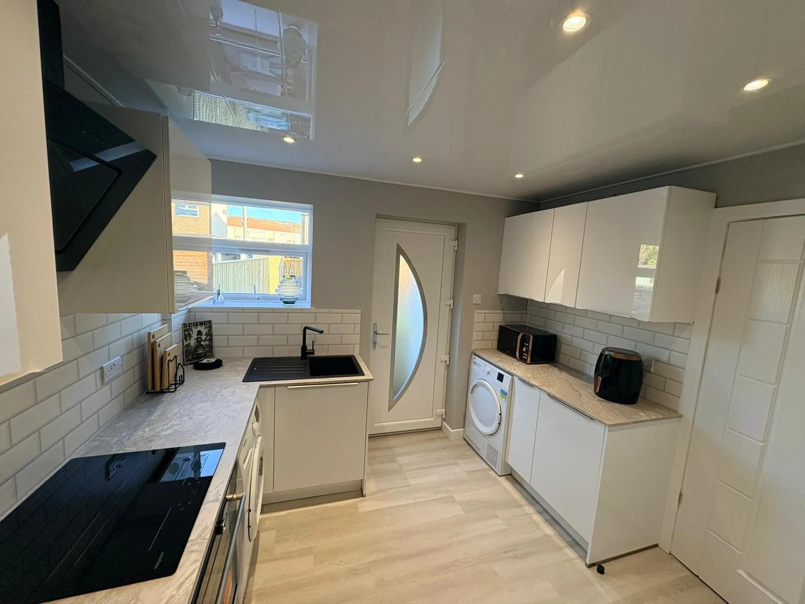 White gloss L-shaped kitchen with angular black hood by Ultimate Home Solutions