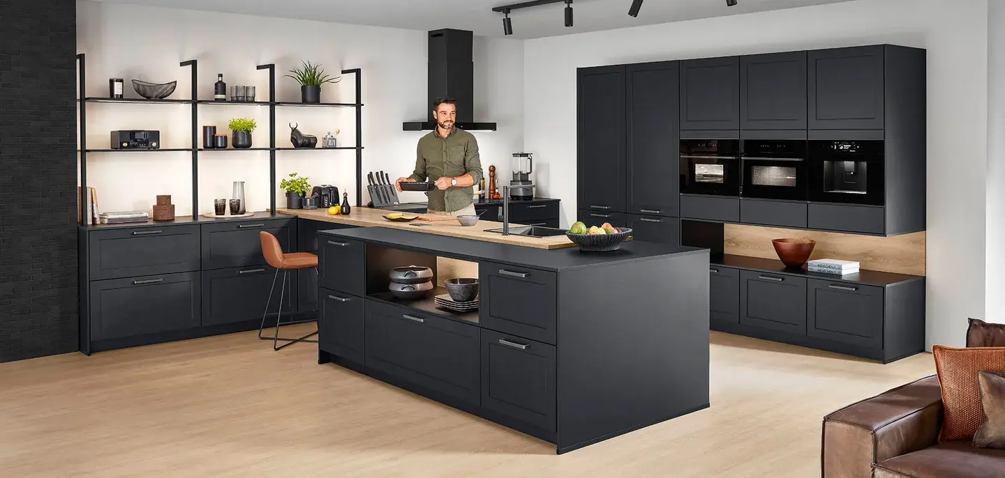 Graphite framed kitchen with an oak breakfast bar, a long island with open shelving and a bank of integrated ovens