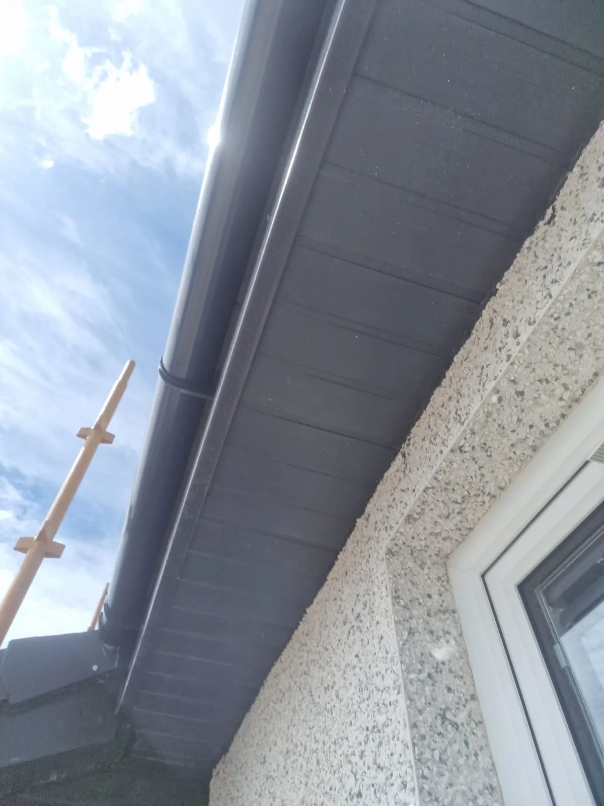 New anthracite-grey soffit, fascia and gutter against dry-dash by Ultimate Home Solutions