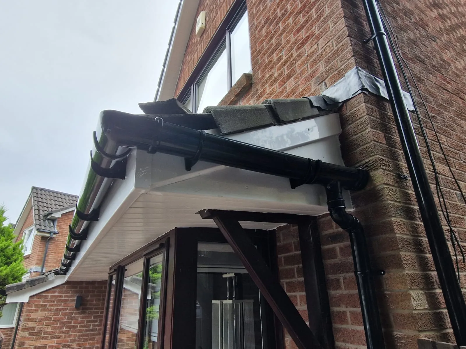 New white fascia and soffit with black half-round gutter on brick by Ultimate Home Solutions
