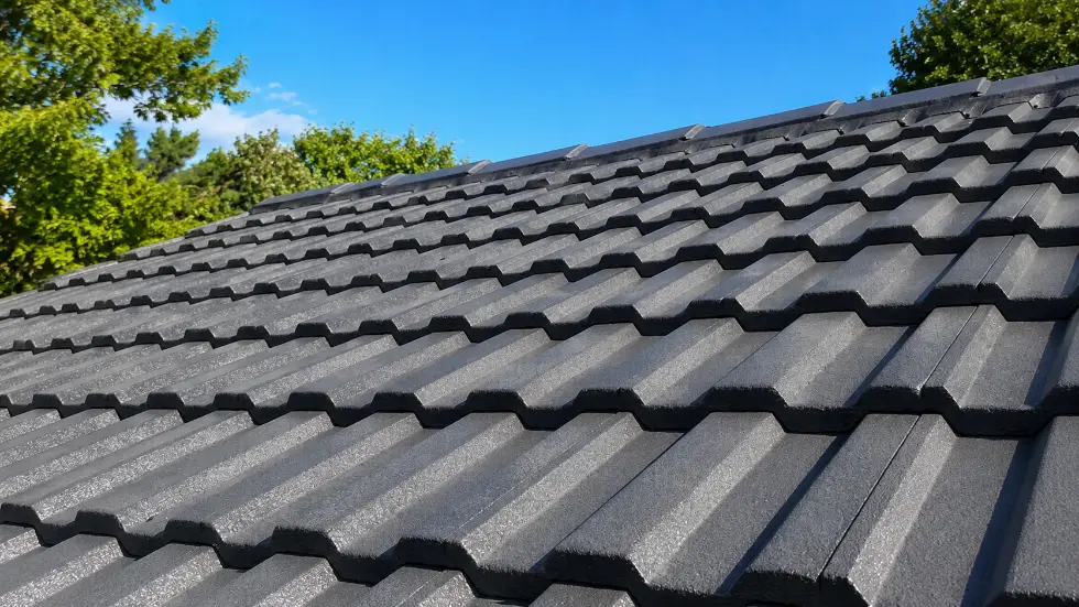 Dark grey concrete tile roof against a blue sky by Ultimate Home Solutions