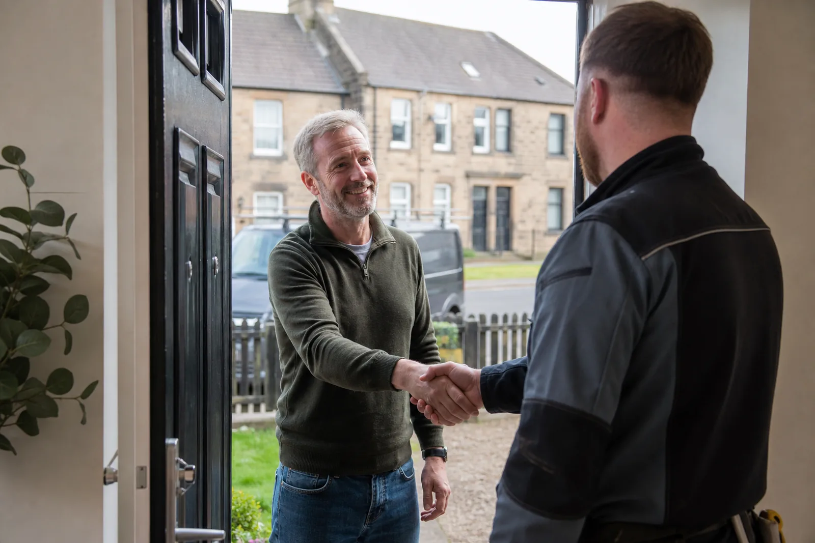 A homeowner shaking hands with a fitter at the front door