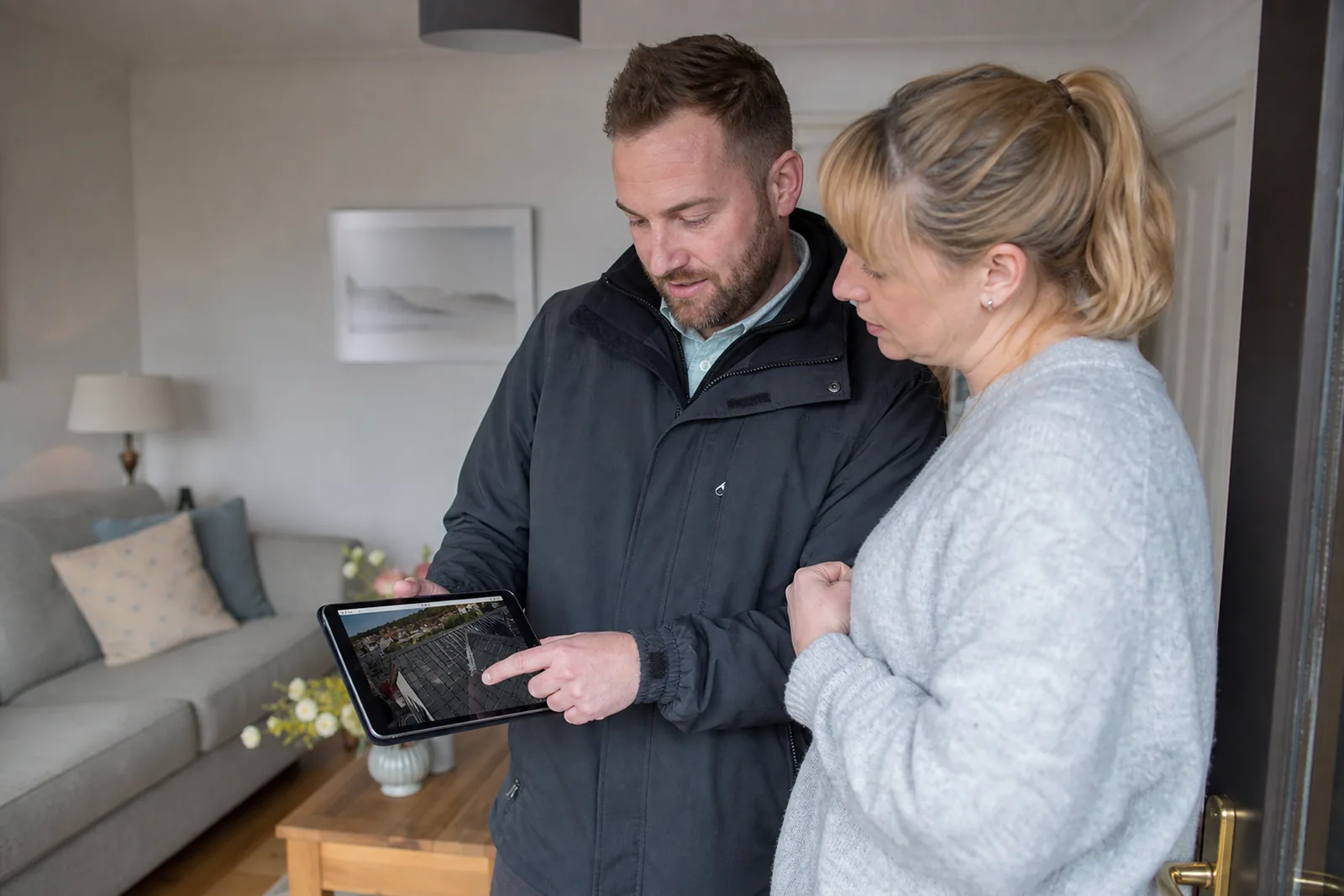 A surveyor going through roof photographs with a homeowner on a tablet